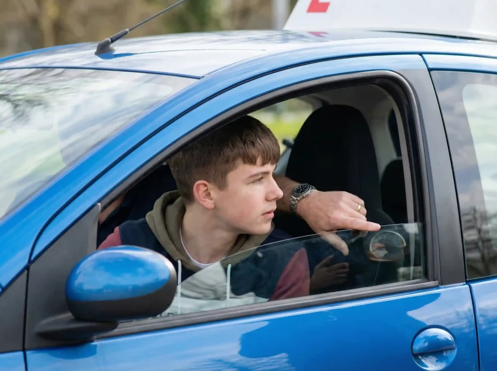 Młody kursant podczas nauki jazdy samochodem na kategorię B1.